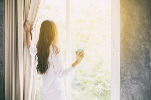 woman opening curtains