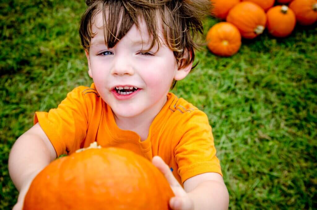 child in garden with halloween pumpkin